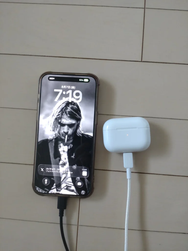 充電ケーブルに接続されたiPhoneと横で充電中のAirPods Pro
